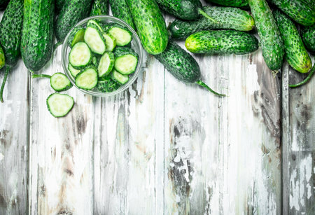 Cucumbers and cucumber slices in a glass bowl. On wooden backgroundの写真素材
