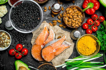 Health food. Salmon steaks with organic vegetables and nuts. On a black rustic background.の写真素材