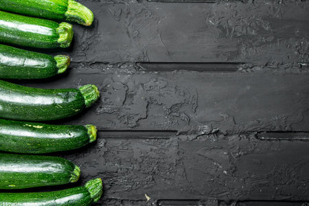Whole fresh zucchini. On black rustic backgroundの写真素材