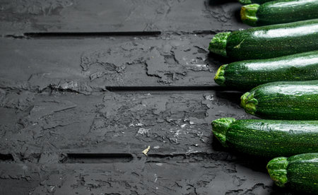 Whole fresh zucchini. On black rustic backgroundの写真素材