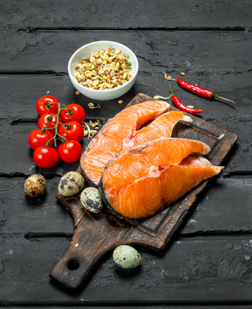 Health food. Salmon steaks with tomatoes and spices. On black rustic background.の写真素材