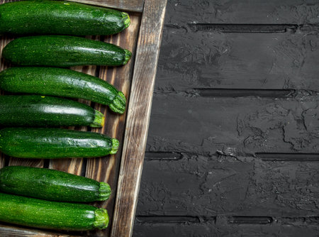 Fresh zucchini on tray. On black rustic backgroundの写真素材