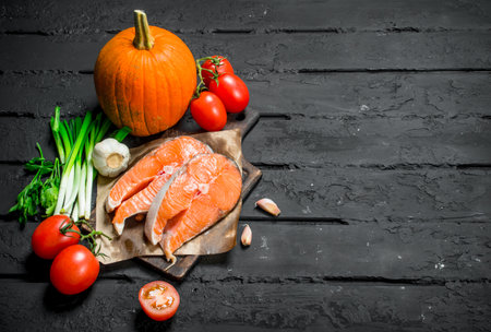 Health food. Salmon with organic vegetables and herbs. On black rustic background.の写真素材