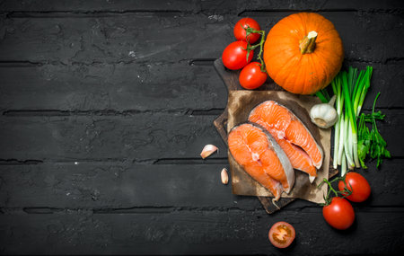 Health food. Salmon with organic vegetables and herbs. On black rustic background.の写真素材
