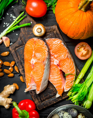 Health food. Salmon with organic vegetables and herbs. On black rustic background.の写真素材