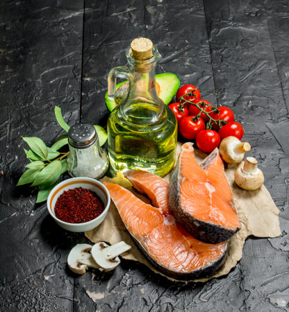 Health food. Salmon steaks with vegetables, herbs and spices. On a black rustic background.の写真素材