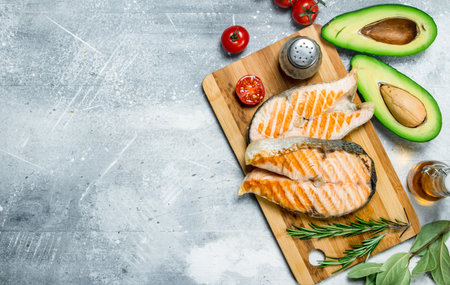Grilled salmon steaks with vegetables on a wooden Board. On a rustic background.の写真素材