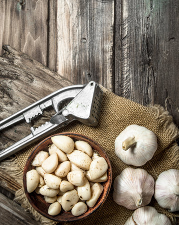 Garlic on a cutting Board with a garlic press. On wooden backgroundの写真素材