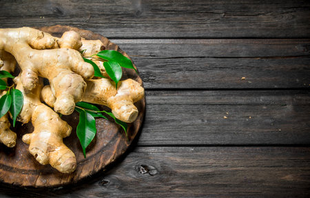 Ginger with leaves on the cutting Board. On wooden backgroundの写真素材