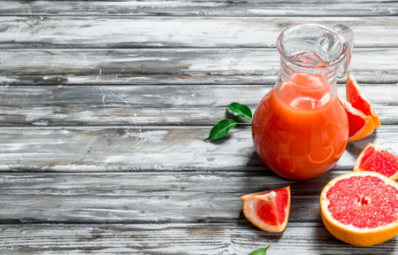 Grapefruit juice in a glass pitcher. On wooden backgroundの写真素材