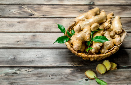 Fragrant ginger with leaves in the basket. On wooden backgroundの写真素材