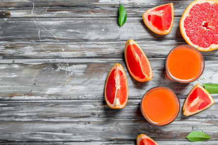 Grapefruit juice in a glass and pieces of fresh grapefruit. On wooden backgroundの写真素材