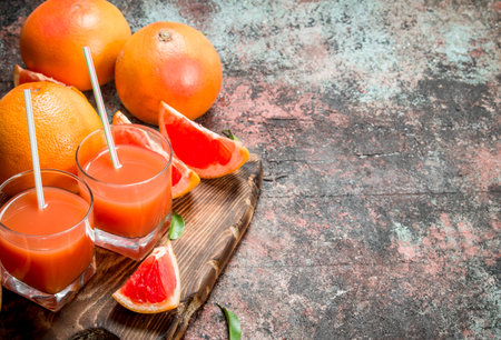 Grapefruit juice in a glass on a cutting Board. On rustic backgroundの写真素材