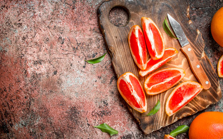 Pieces of grapefruit on a cutting Board with a knife. On rustic backgroundの写真素材