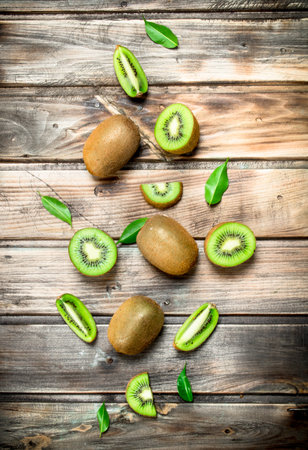 Ripe juicy kiwi with leaves. On wooden backgroundの写真素材