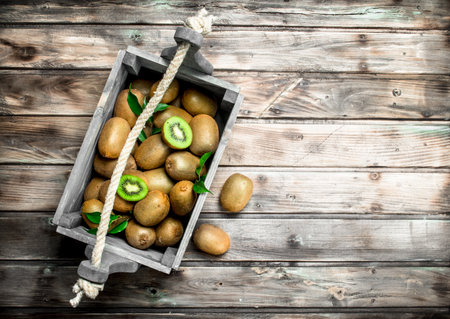 Ripe kiwi in a wooden box. On wooden backgroundの写真素材