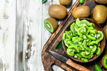 Kiwi slices in a bowl on a cutting Board with a knife. On wooden backgroundの写真素材