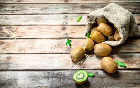 Ripe kiwi with leaves in an sack. On wooden backgroundの写真素材
