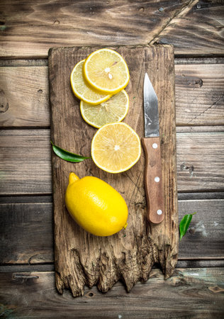 Sliced lemon on a cutting Board with a knife. On wooden backgroundの写真素材