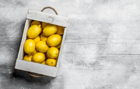 Fresh yellow lemons in wooden box. On rustic backgroundの写真素材