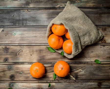 Fresh tangerines in the sack. On wooden backgroundの写真素材