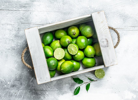 Fresh juicy lime in the box. On white rustic backgroundの写真素材