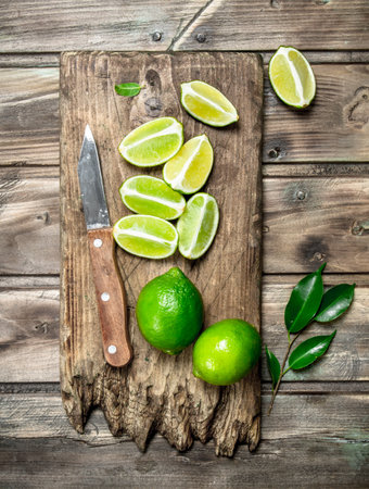 Pieces of fresh lime on a cutting Board with a knife. On wooden backgroundの写真素材