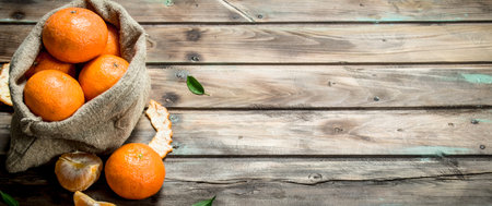 Fresh tangerines in the sack. On wooden backgroundの写真素材
