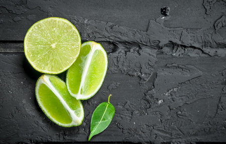Slices of fresh juicy lime. On black rustic backgroundの写真素材