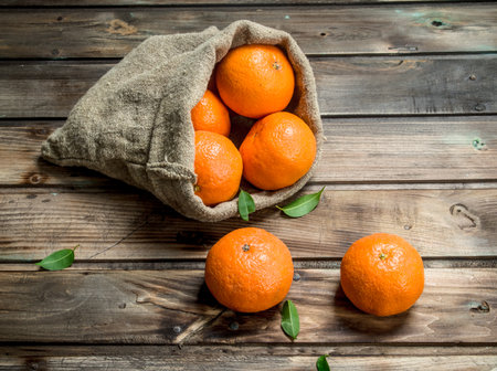 Fresh tangerines in the sack. On wooden backgroundの写真素材
