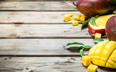 Pieces of mango with leaves. On wooden backgroundの写真素材