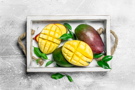 Fresh ripe mangoes in the tray. On rustic backgroundの写真素材