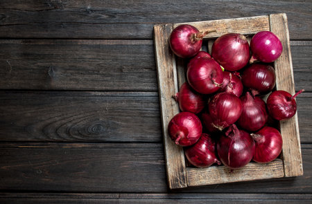 Fresh red onions in tray. On wooden backgroundの写真素材