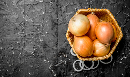 Onions in basket and onion rings. On rustic backgroundの写真素材