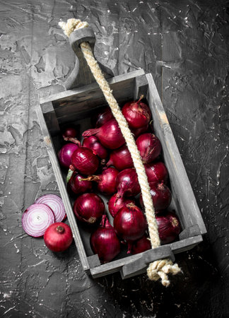 Fragrant red onion in the box. On black rustic backgroundの写真素材