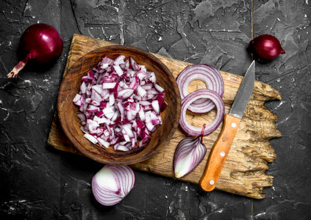 Sliced red onion in bowl and onion rings on cutting Board with knife. On rustic backgroundの写真素材