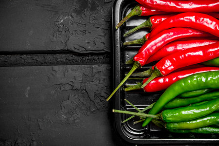 Hot fresh pepper on tray. On black rustic backgroundの写真素材