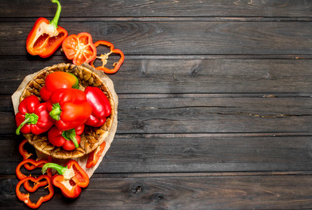 Sweet pepper in a basket and pieces of fresh pepper. On wooden backgroundの写真素材