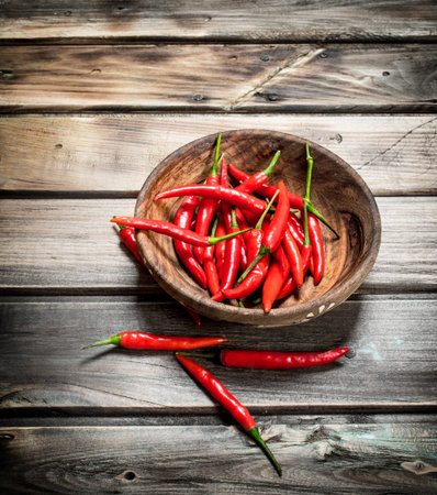 Fresh ripe red pepper in wooden bowl. On wooden backgroundの写真素材