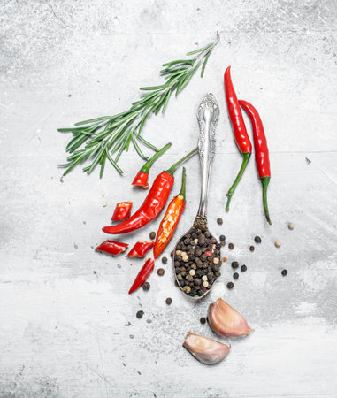Pepper peas in a spoon with pieces of red pepper, rosemary and garlic. On rustic backgroundの写真素材