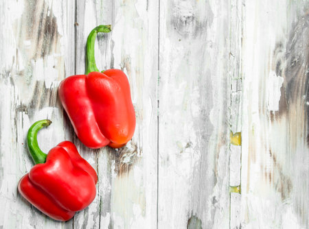 Two fresh sweet red peppers. On white wooden backgroundの写真素材