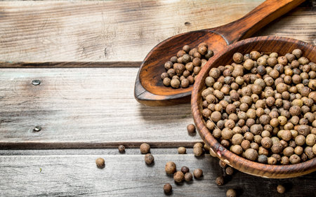 Black pepper in a bowl and spoon. On wooden backgroundの写真素材