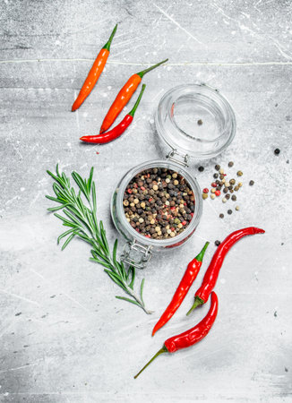 Pepper peas in a glass jar with red hot pepper and rosemary. On rustic backgroundの写真素材