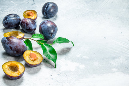 Whole and pieces of plum. On white rustic backgroundの写真素材