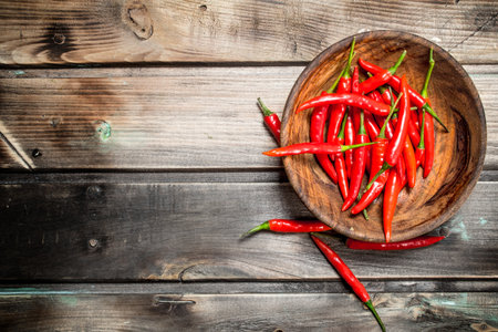 Fresh ripe red pepper in wooden bowl. On wooden backgroundの写真素材