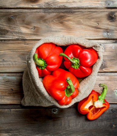 Fresh red sweet pepper in the sack and a half of ripe pepper. On wooden backgroundの写真素材