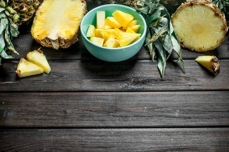 Fragrant slices of ripe pineapple in a bowl. On wooden backgroundの写真素材