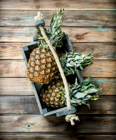 Fragrant pineapples in the box. On wooden backgroundの写真素材