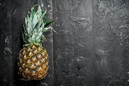 One fresh ripe pineapple. On black rustic backgroundの写真素材