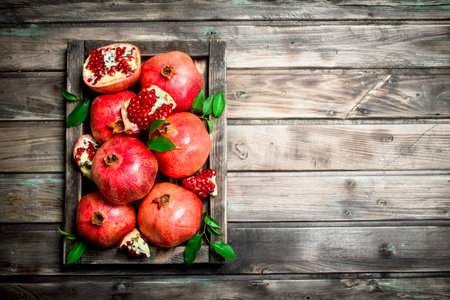Juicy pomegranates on the tray. On wooden backgroundの写真素材